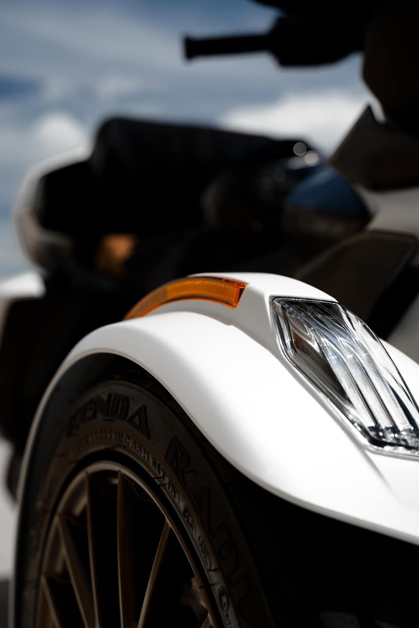 Close-up of a white vehicle front wheel and fender with amber turn signal detail