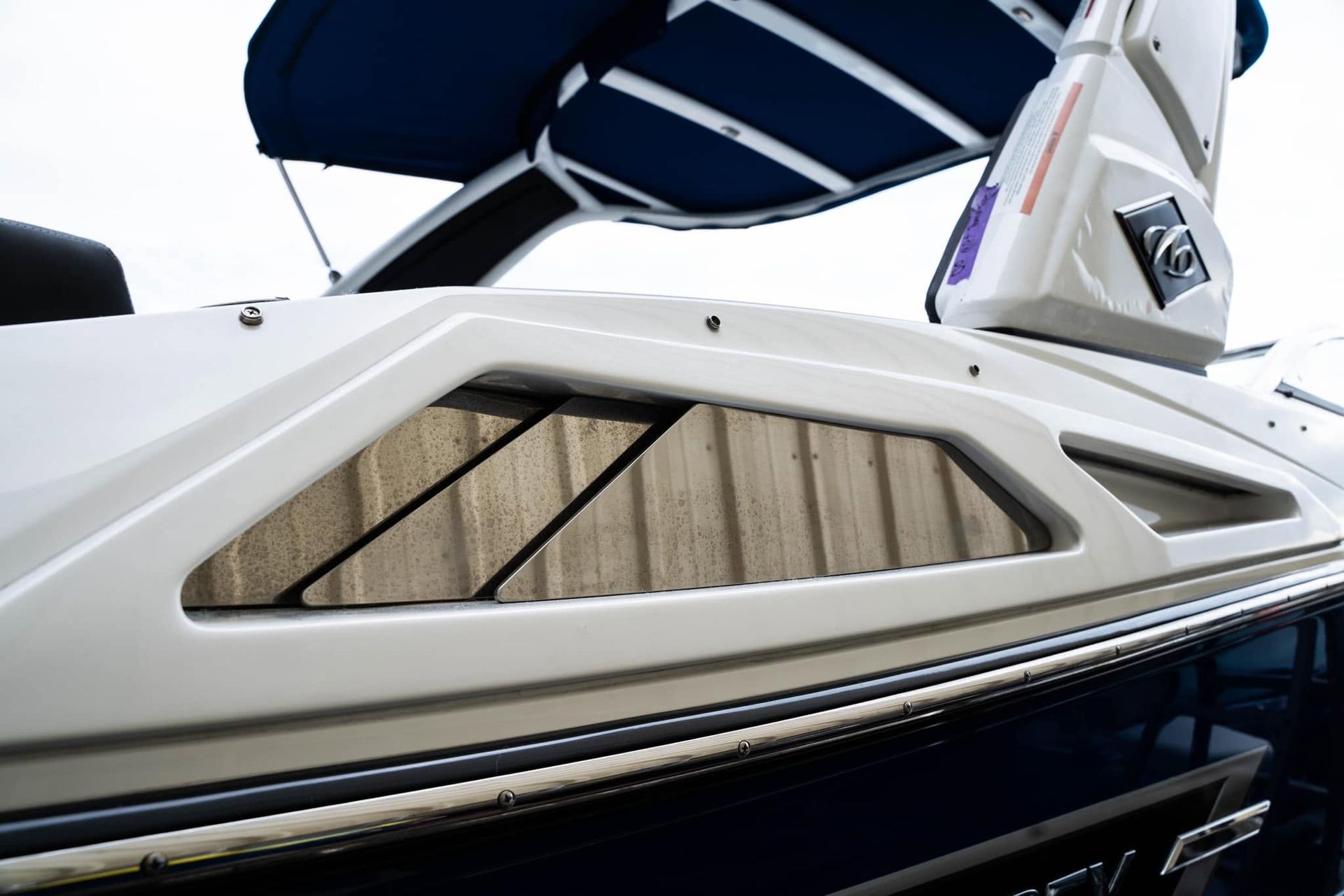 White boat hull with tinted side window and dark blue canopy on the water