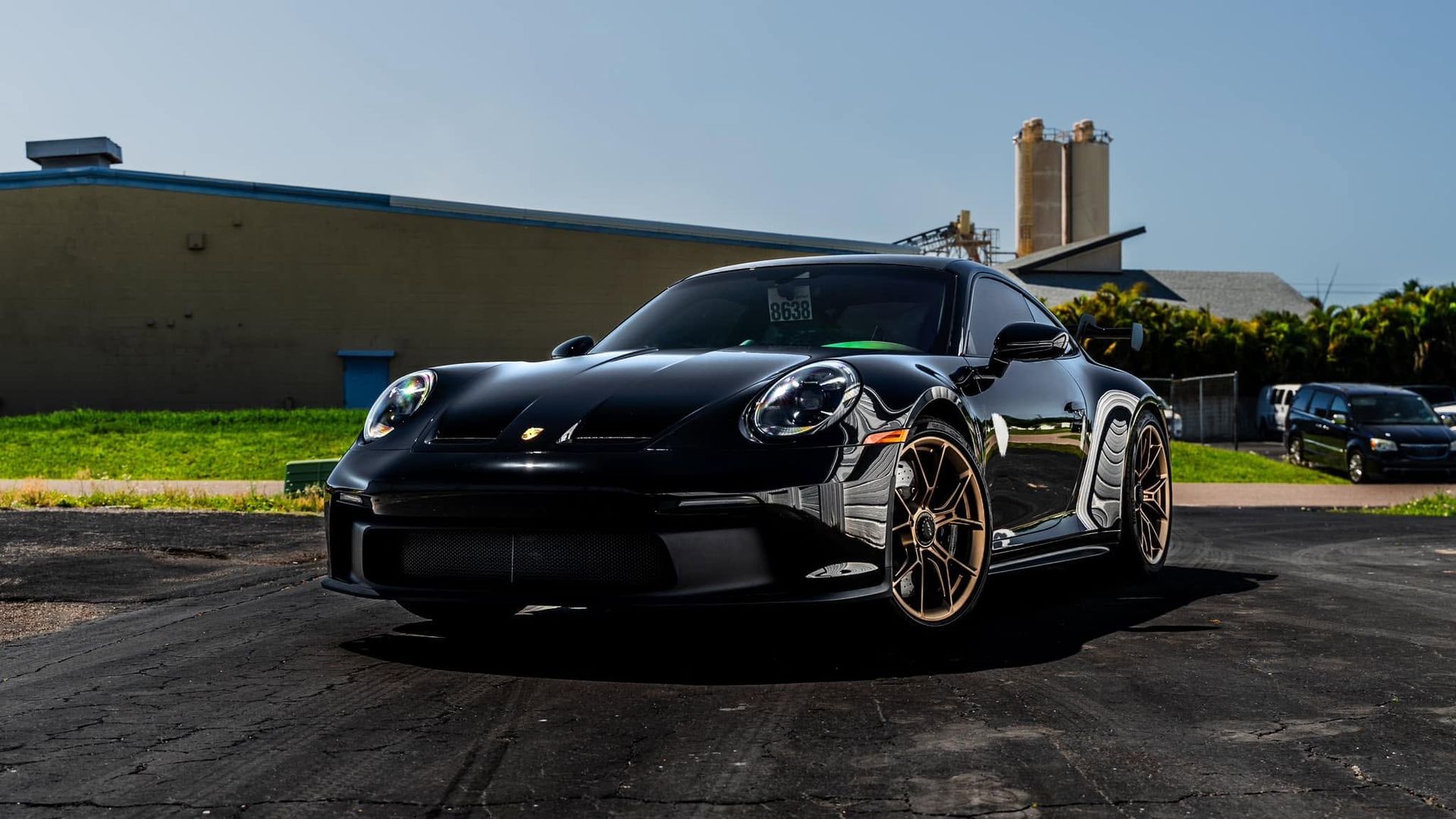Black sports car parked on a sunny street in front of a low beige building