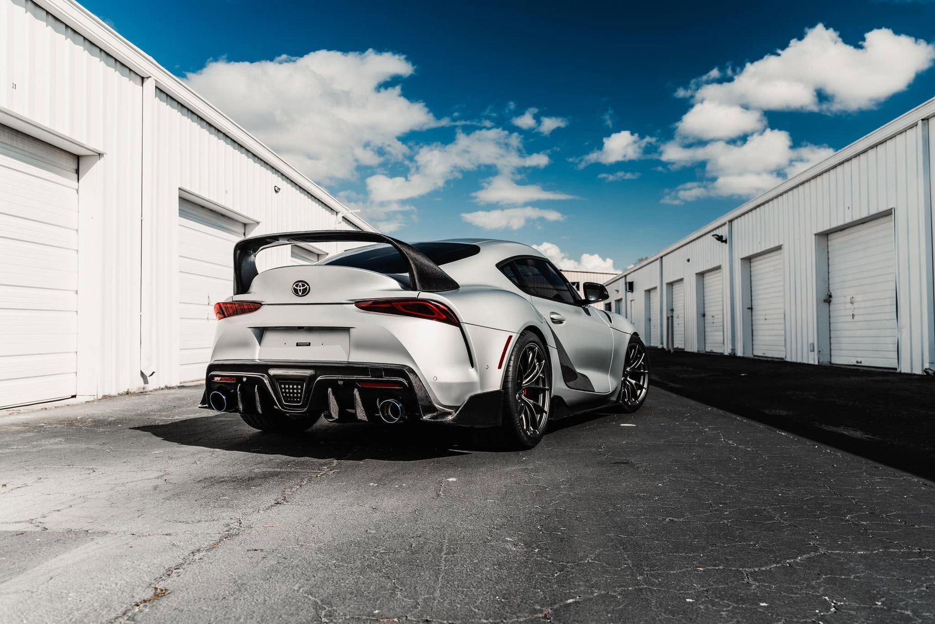 White sports car parked between storage units under a blue sky