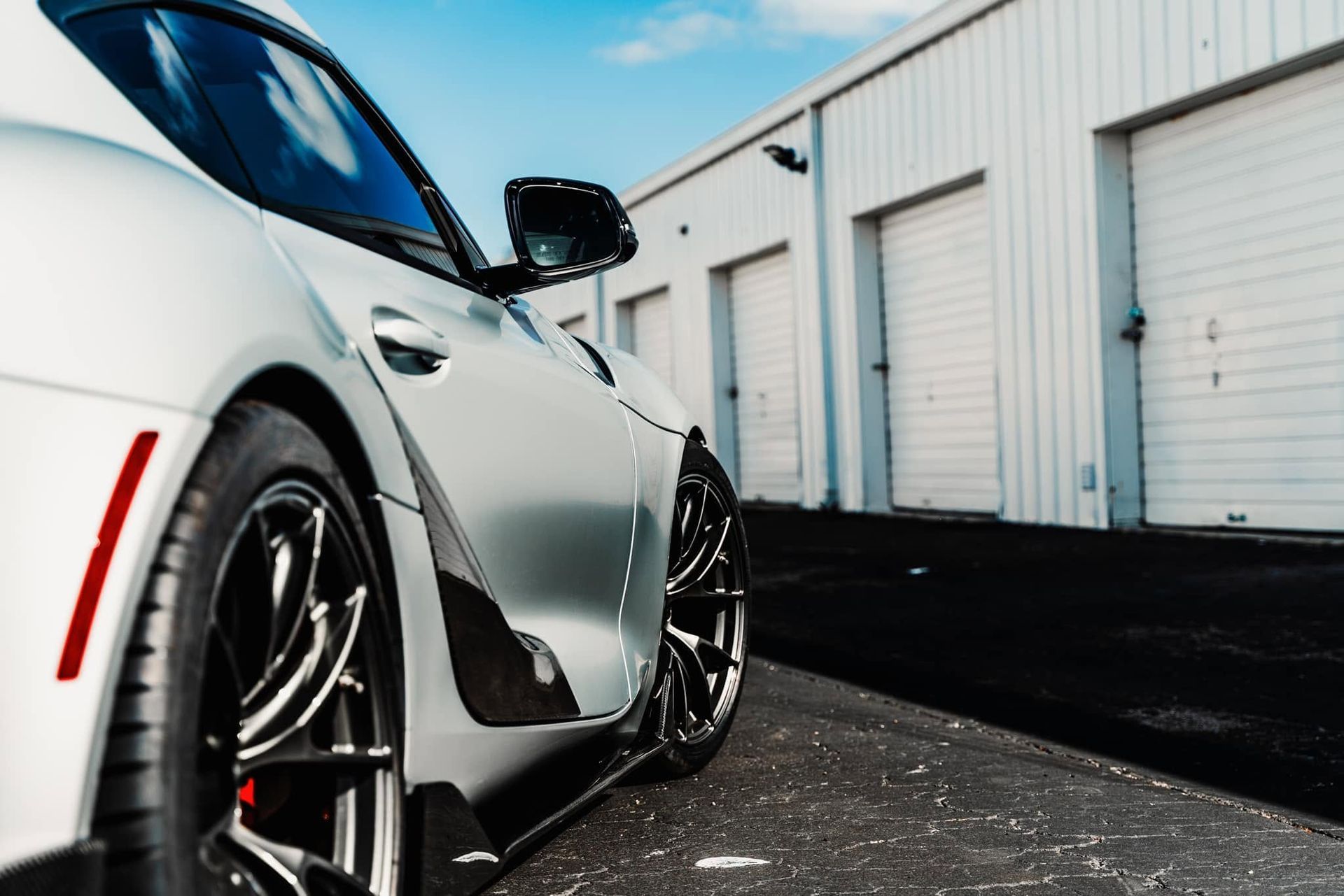 Silver sports car parked beside white warehouse doors