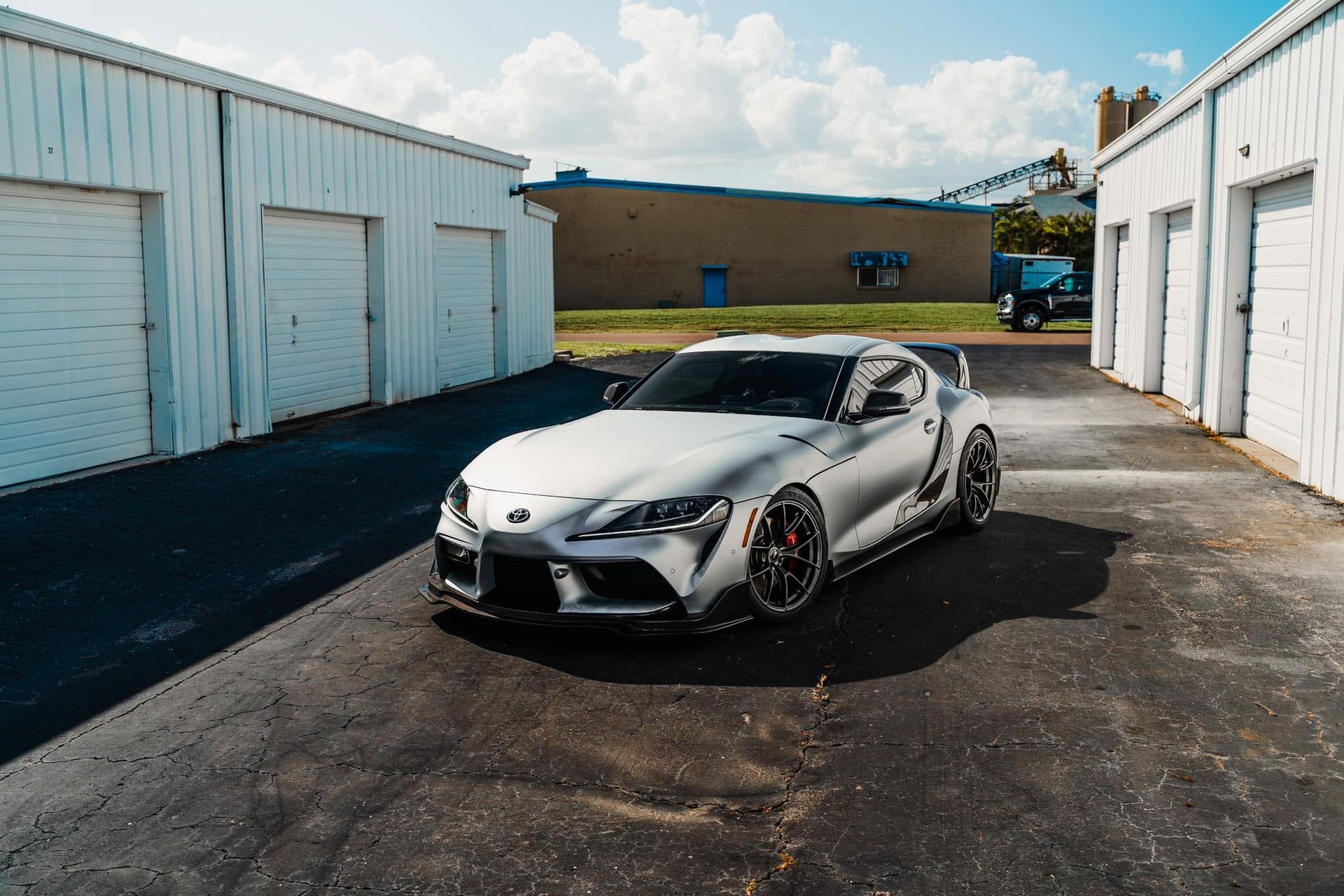 Silver sports car parked between white garage units on a sunny lot