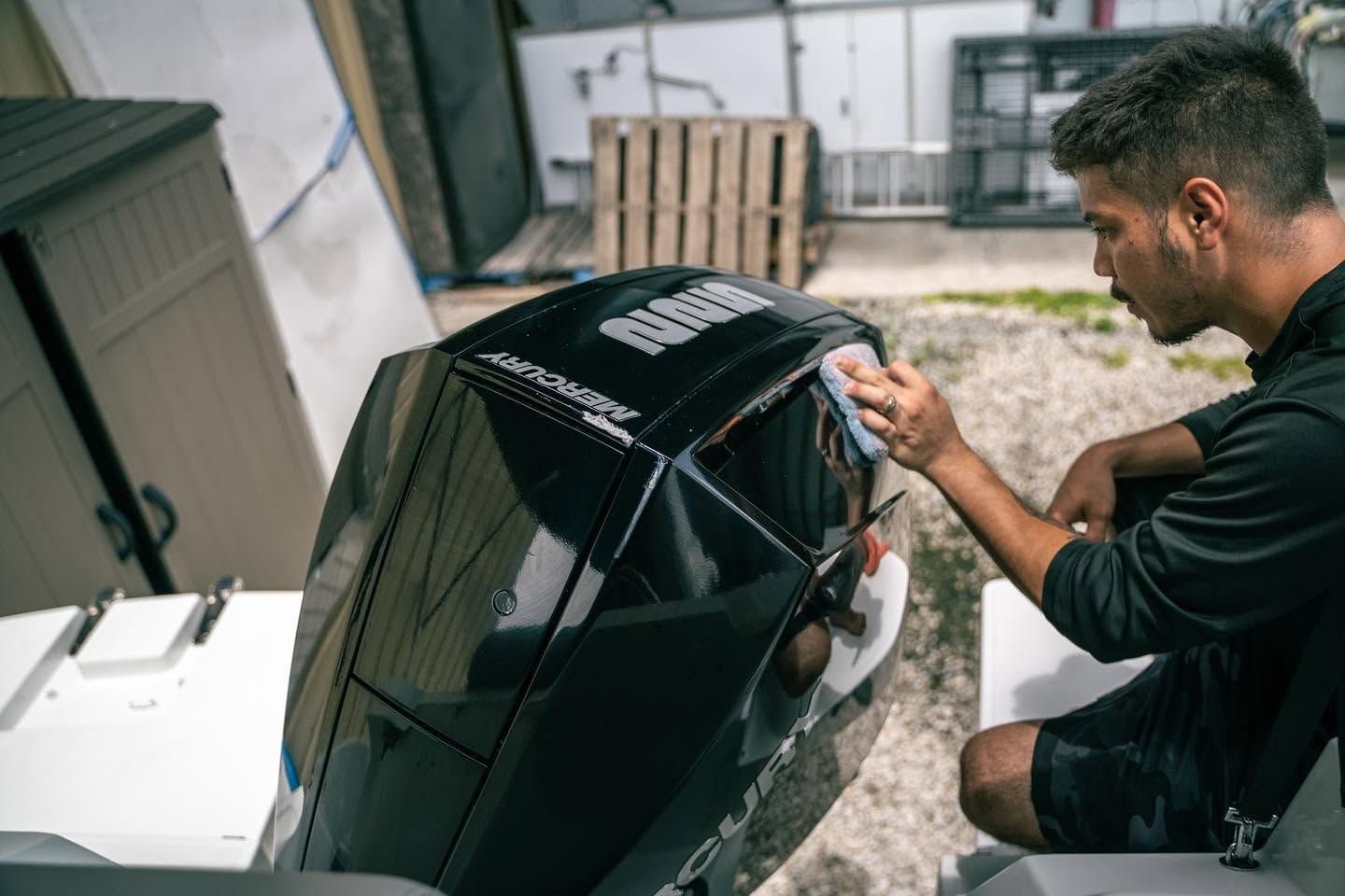 Person working on a glossy black boat engine outdoors