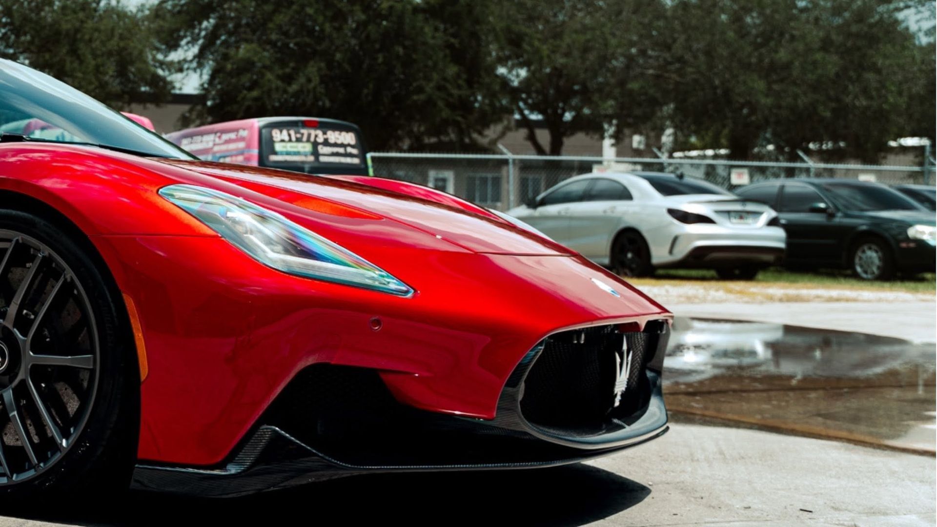 Red sports car parked on a wet street in front of other parked cars