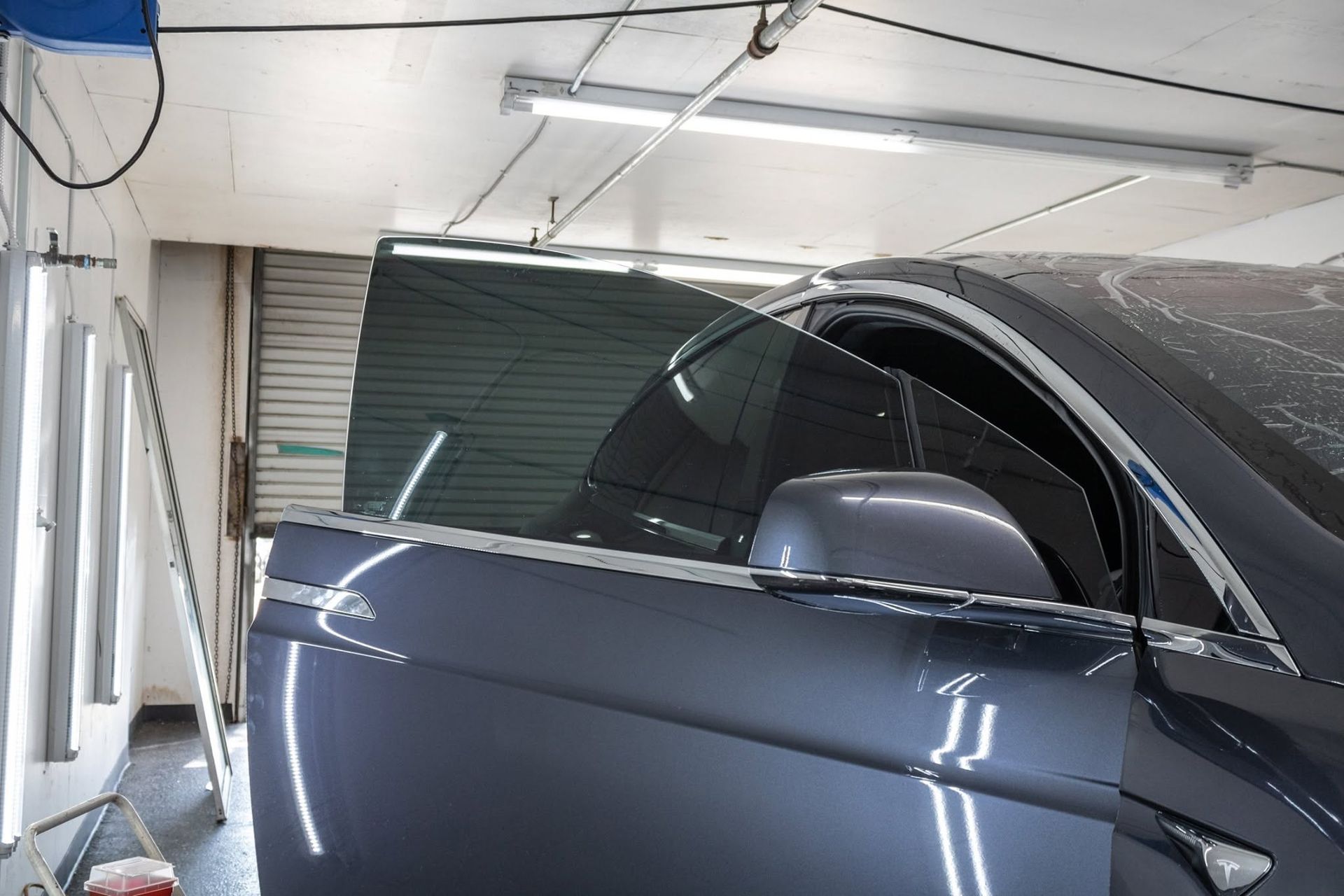 Dark gray car parked inside a garage with its side mirror and window visible