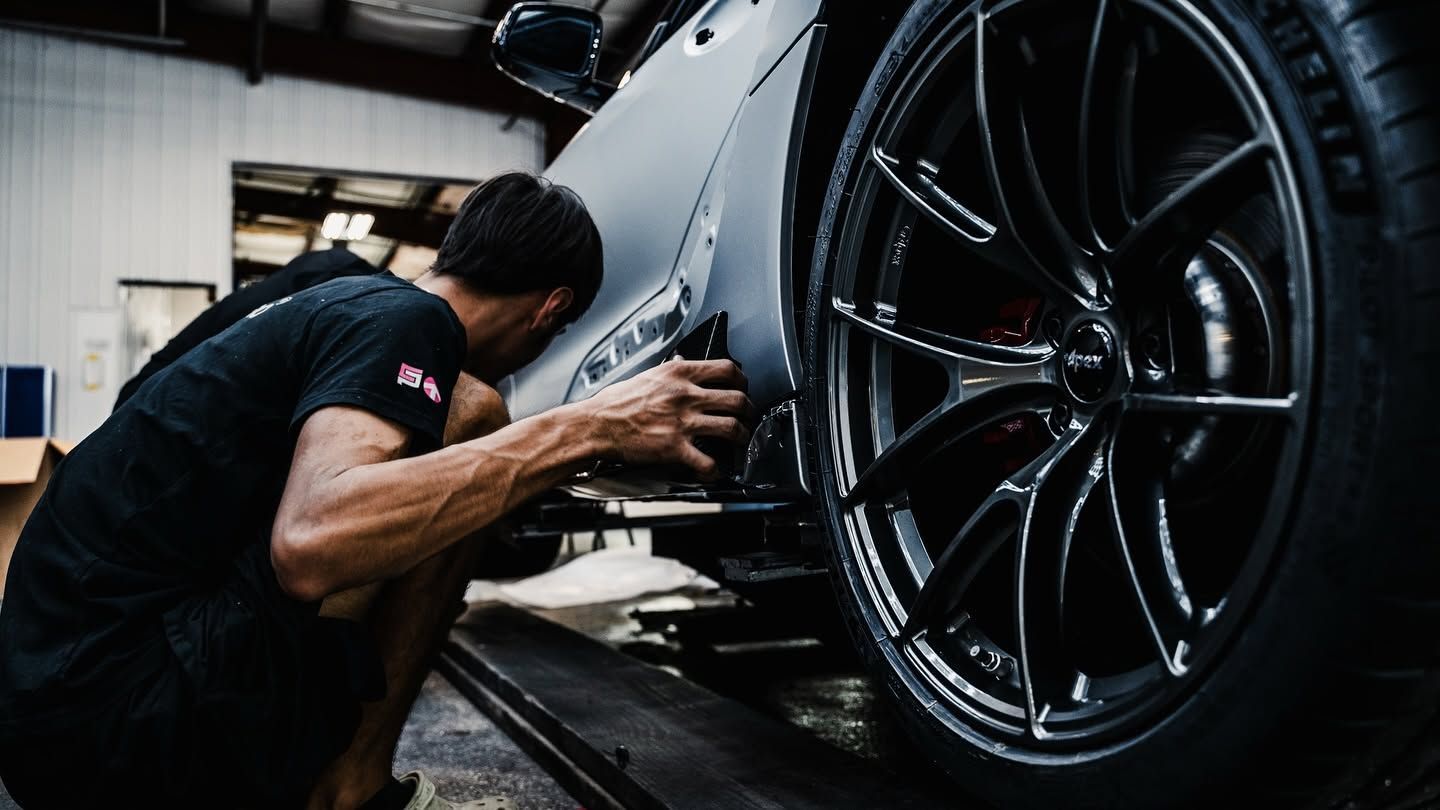 Mechanic adjusting a black sports car’s wheel in an auto shop