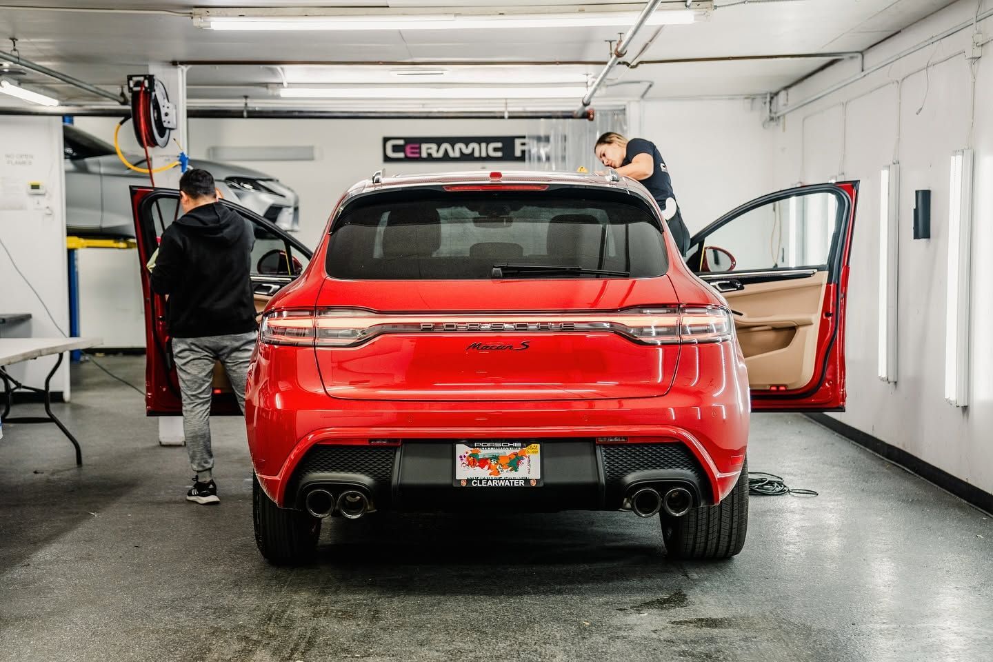 Red SUV in a garage with two people working on it, rear doors open