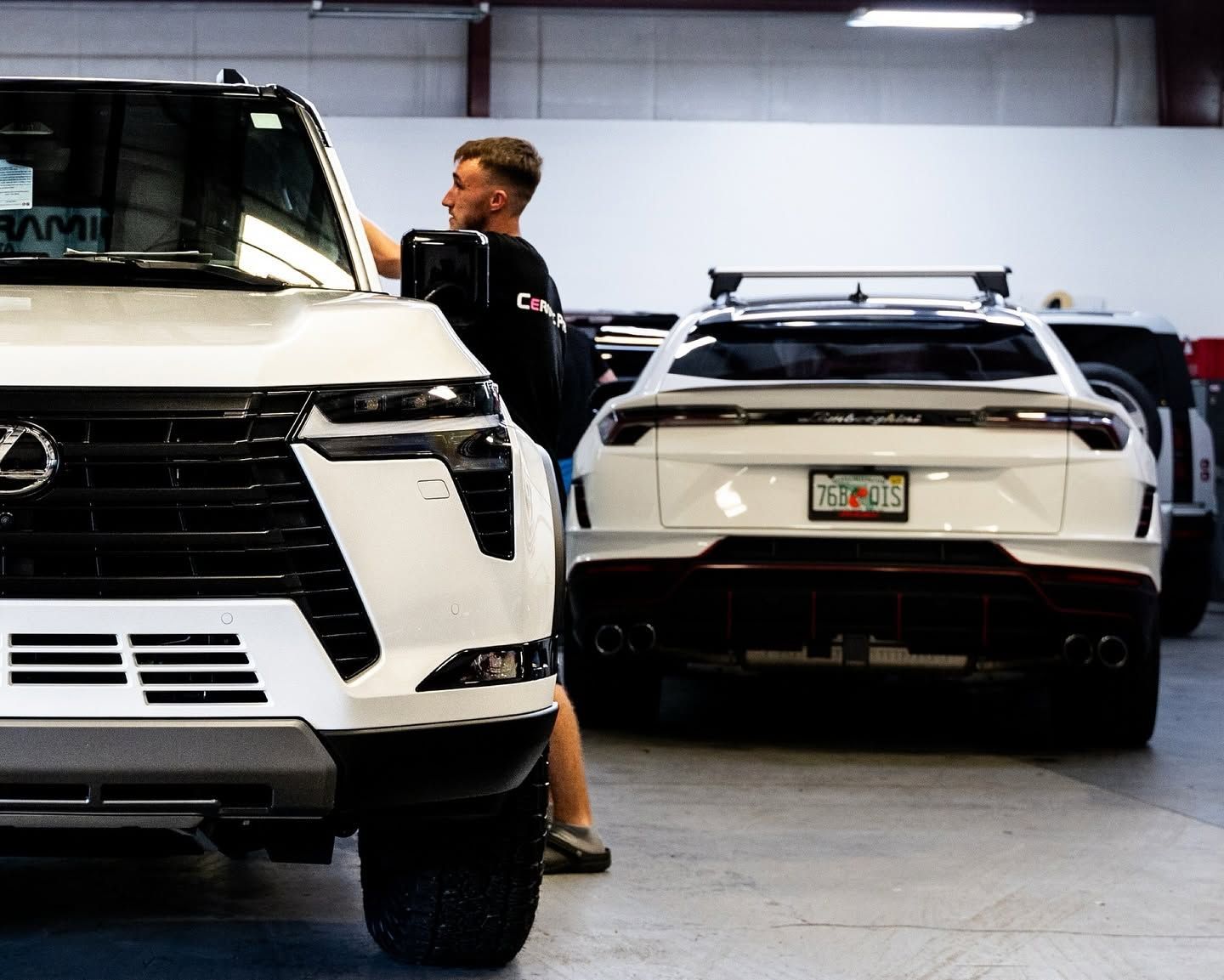 White SUVs in a garage, with a person standing between them near the front vehicle.
