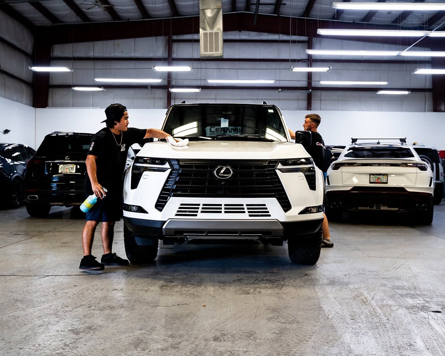Two people beside a white Lexus SUV in a garage, with other cars parked behind them.