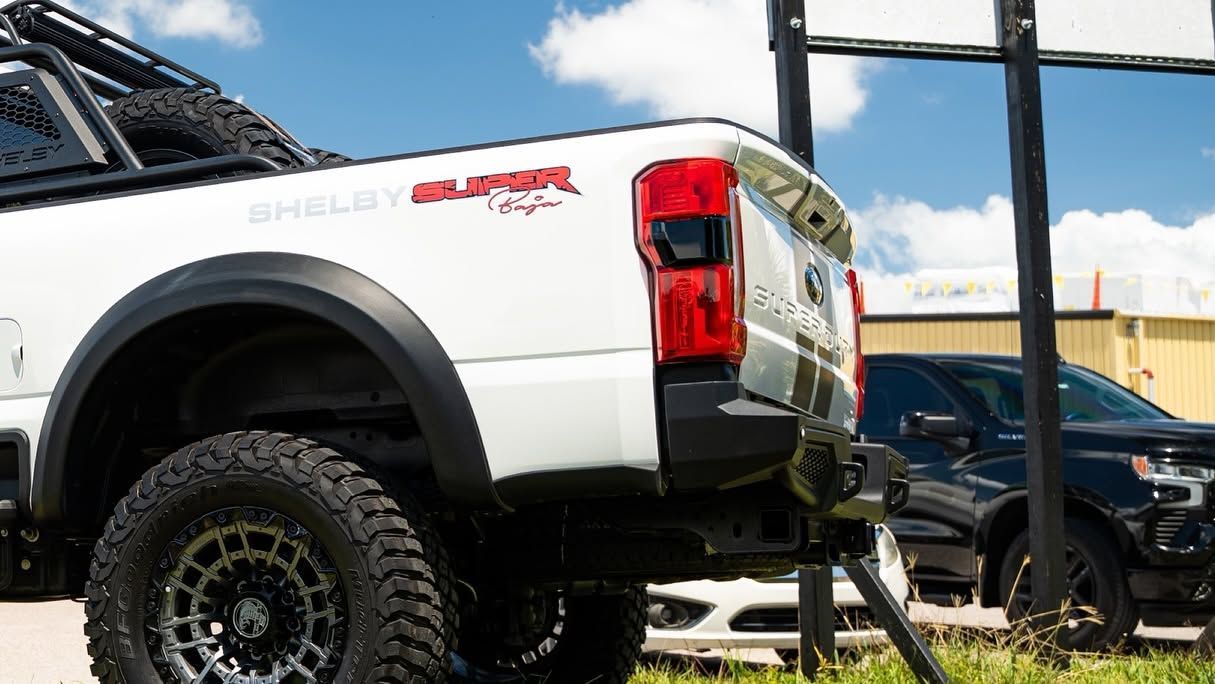 White pickup truck with off-road tires parked outdoors under a blue sky