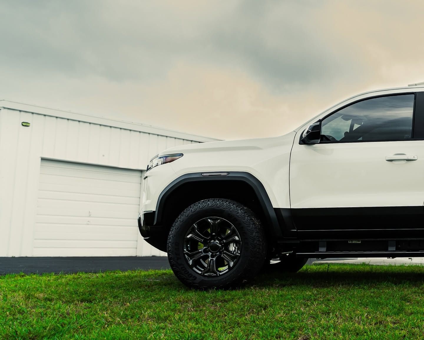 White SUV parked on grass beside a white garage under an overcast sky