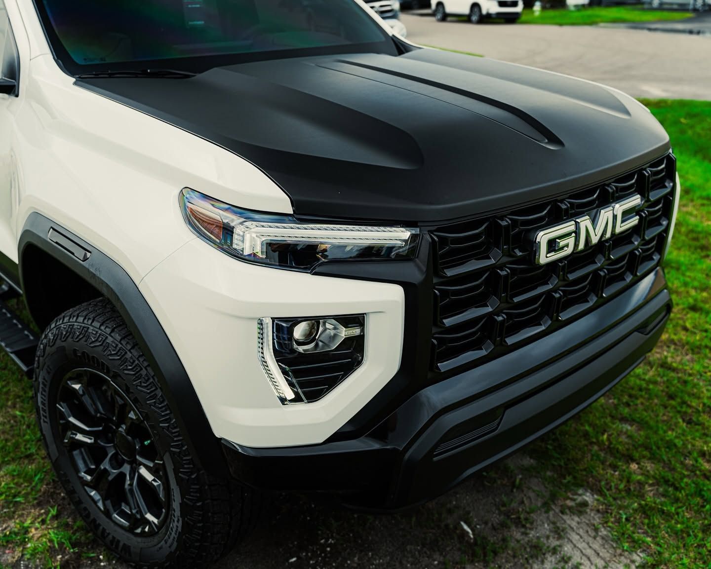 White GMC SUV with matte black hood and grille, parked outdoors on grass