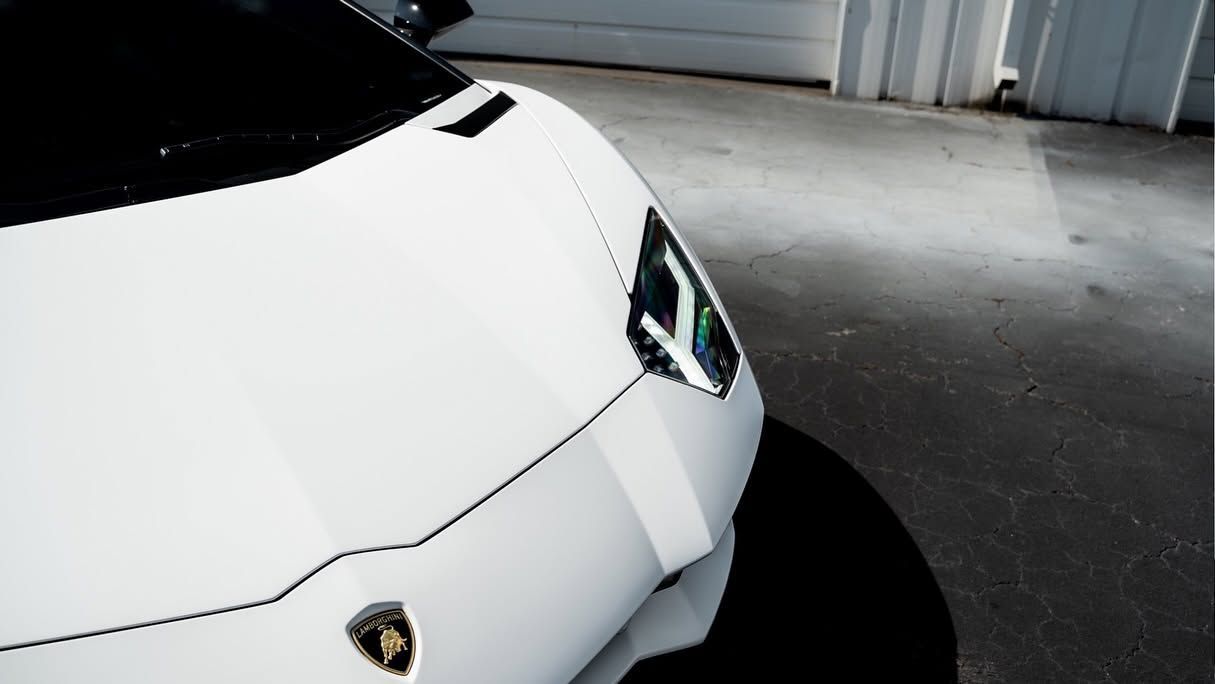 White Lamborghini parked in a garage, front-left view on a concrete floor.