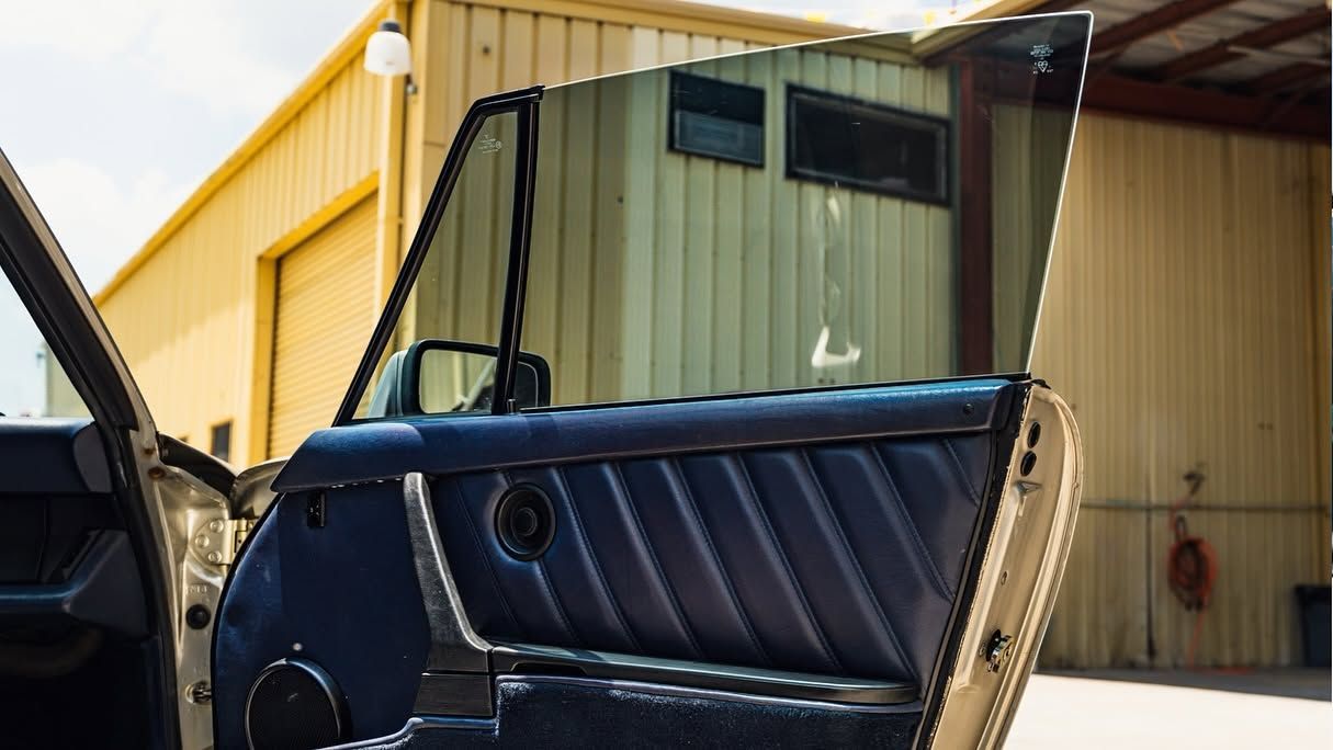 Black car door open in front of a yellow industrial building