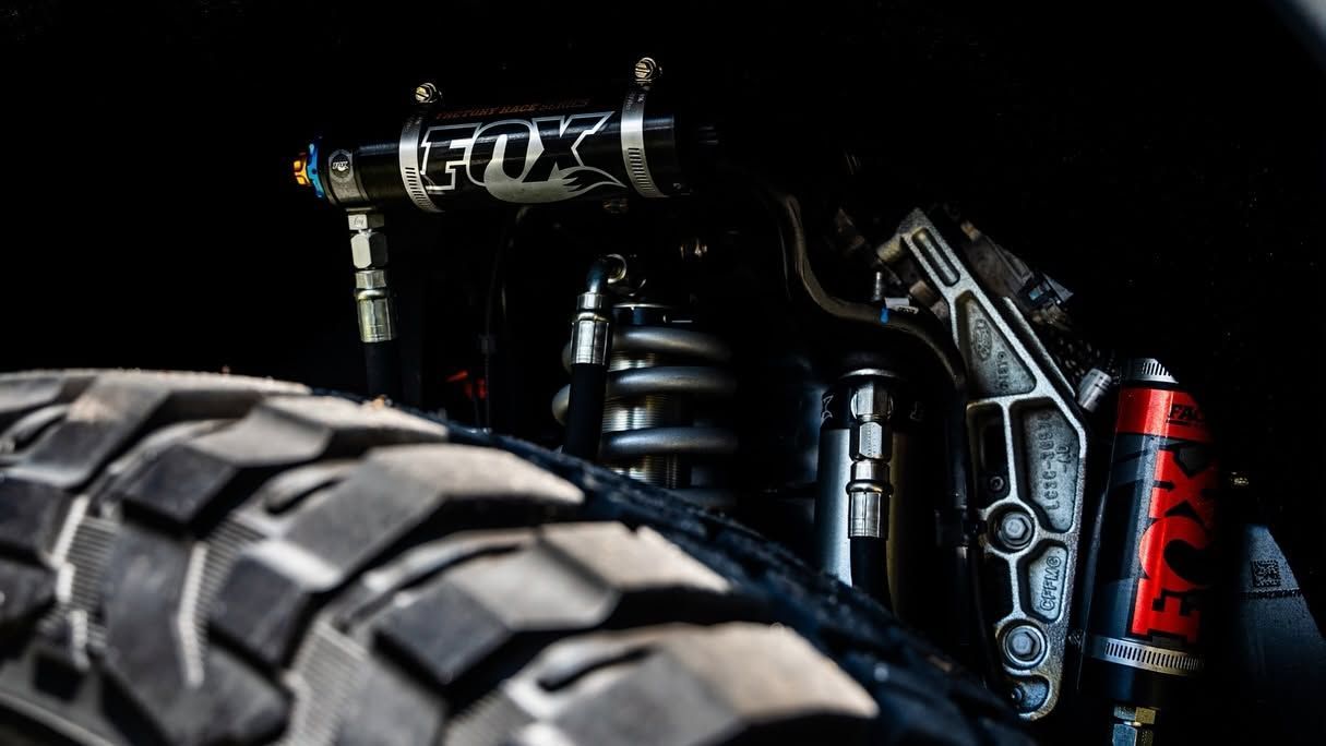 Close-up of a Fox mountain bike fork and wheel against a dark background