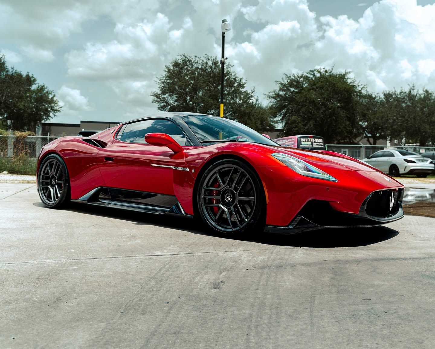 Red sports car parked outdoors on a road under a cloudy sky