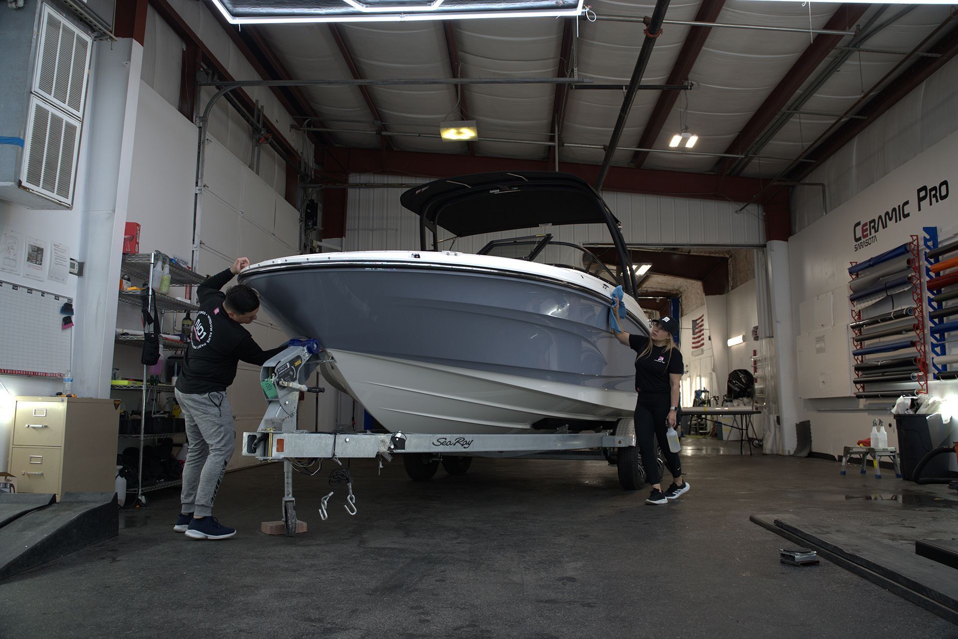 Boat being serviced in a garage, with two people working on a silver speedboat.
