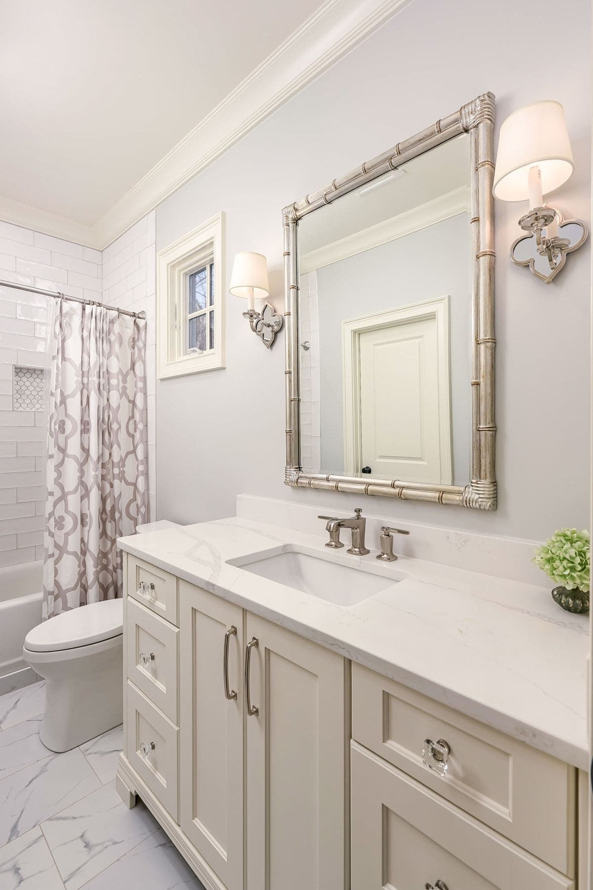 Bright white bathroom with vanity, mirror, sink, toilet, and shower curtain.