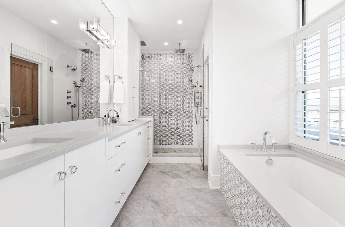 Bright white bathroom with double vanity, large tub, and tiled walk-in shower.