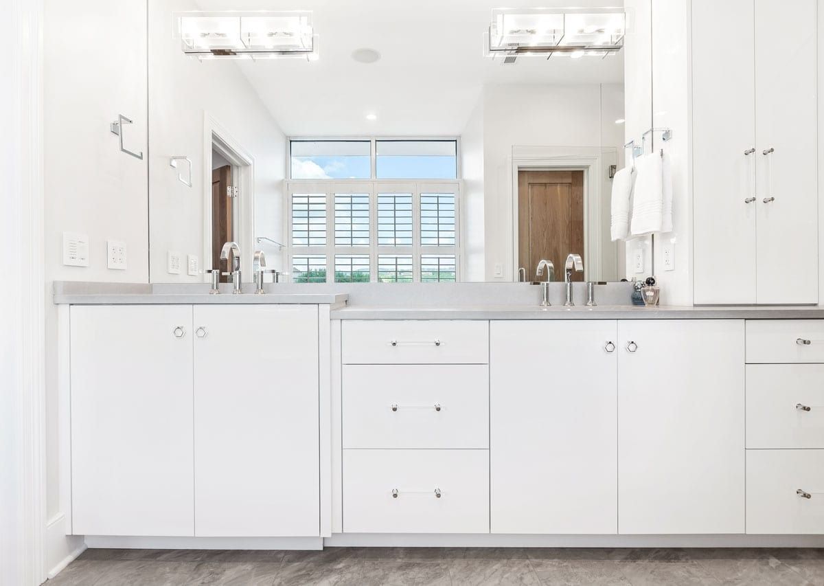 Bright white kitchen with cabinets, gray countertop, and large window overlooking a pool.