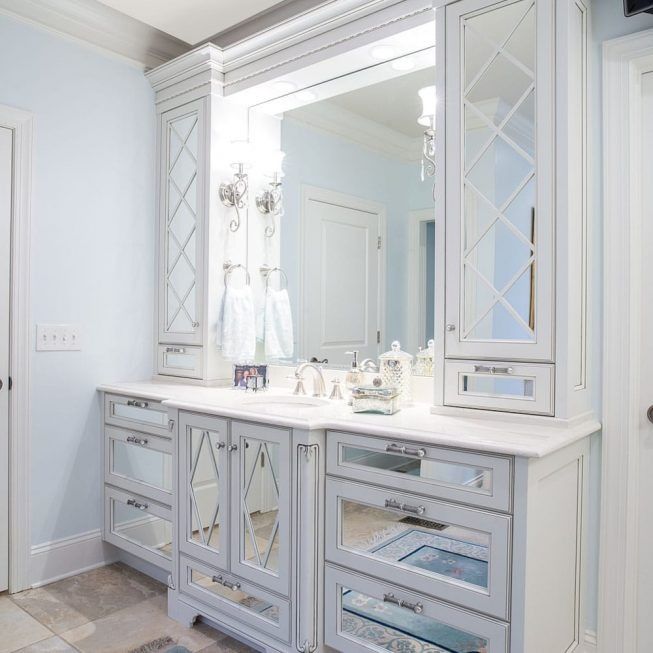 Bright white bathroom vanity with mirrored cabinets and silver accents in a sunlit room