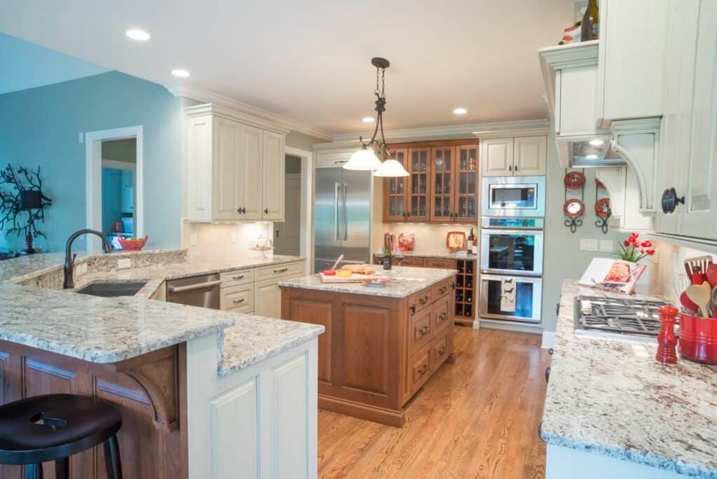Bright modern kitchen with white cabinets, granite island, wood floors, and stainless steel appliances