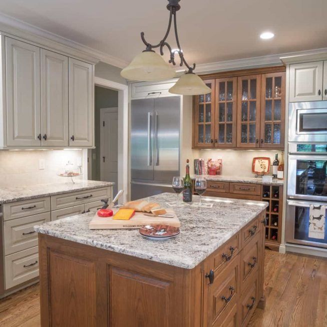 Modern kitchen with a large granite island, light cabinets, stainless appliances, and hanging pendant lights