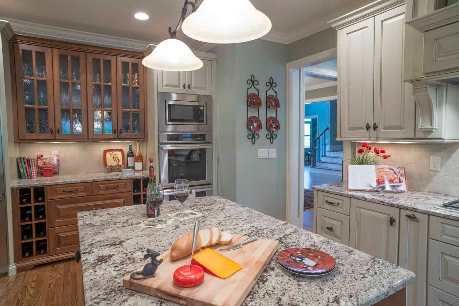 Modern kitchen with granite island, white cabinets, wood dining area, and pendant lights