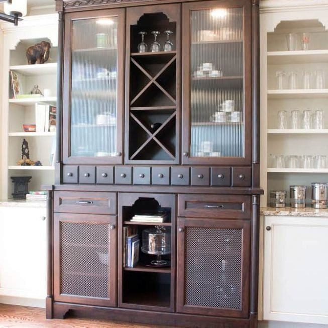 Dark wood china cabinet with glass doors, shelves, and drawers, flanked by white built-in cabinets.