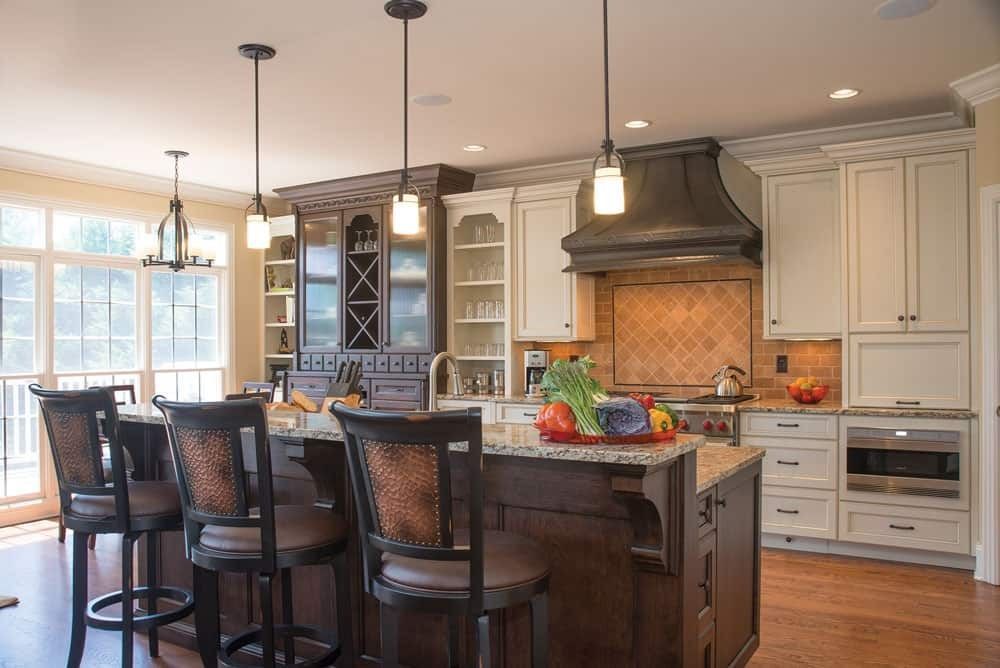Modern kitchen with island, pendant lights, bar stools, white cabinets, and brick backsplash