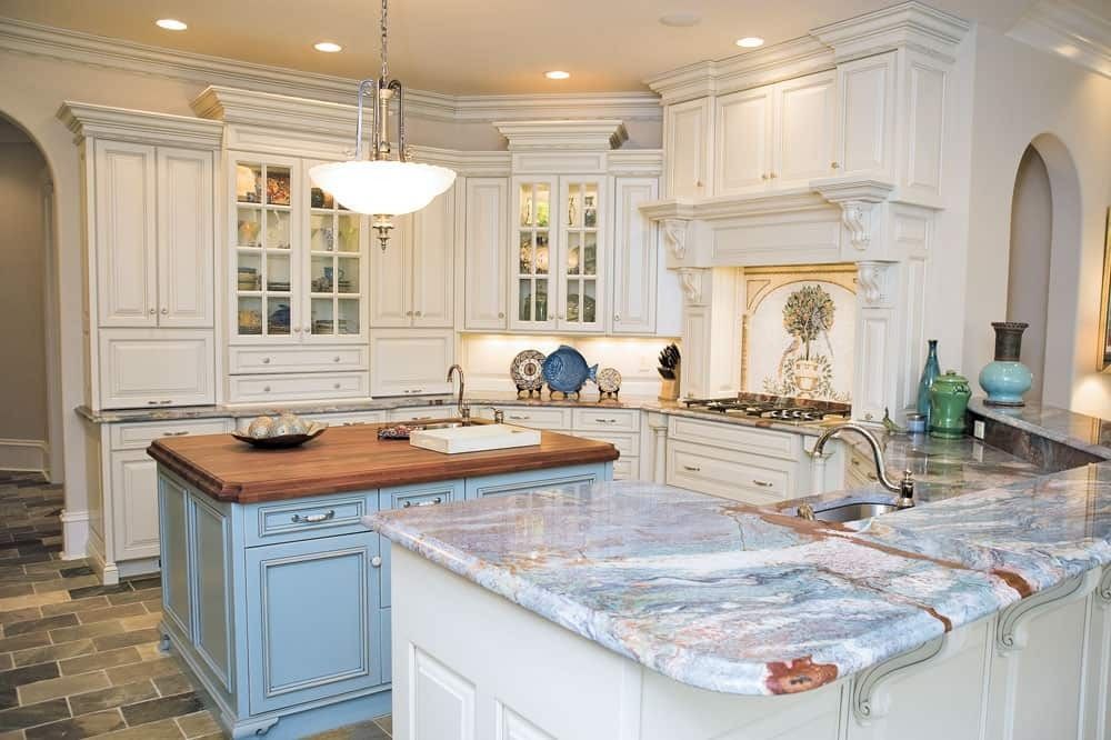 Bright white kitchen with blue island, marble countertops, and pendant lighting