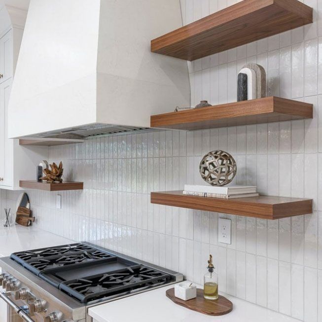 Modern kitchen with gas stove, white tiled backsplash, and floating wood shelves