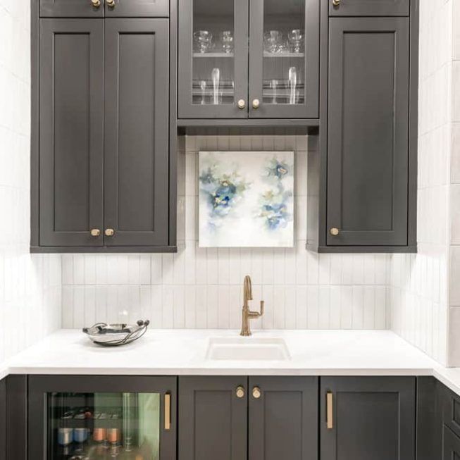 Modern kitchen with dark cabinets, white countertop, brass faucet, and floral wall art