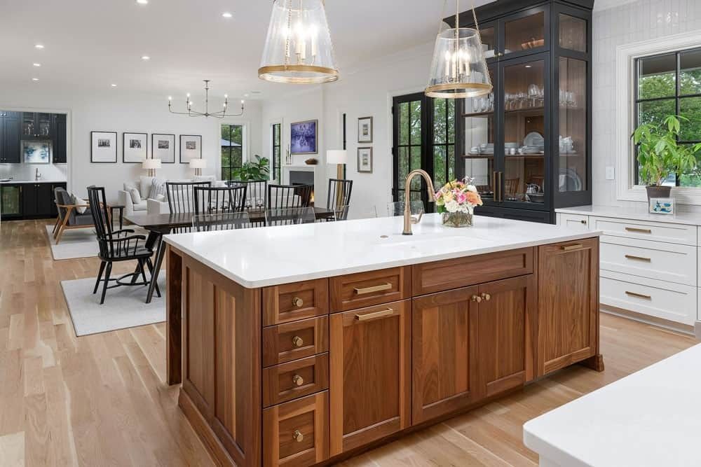 Spacious modern kitchen with a large wood island, white cabinets, and open dining area beyond.