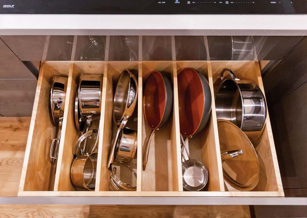 Drawer organizer with nested pots, pans, and lids in a kitchen cabinet