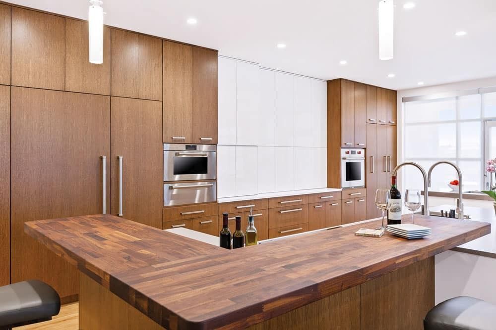 Modern kitchen with wood cabinets, large island, stainless appliances, and bright white lighting