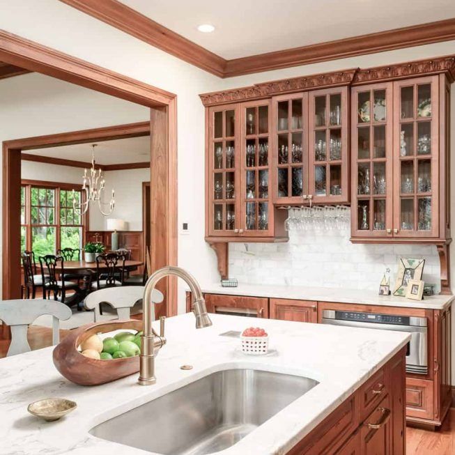 Bright kitchen with white island, wood cabinets, and a dining area beyond the open doorway