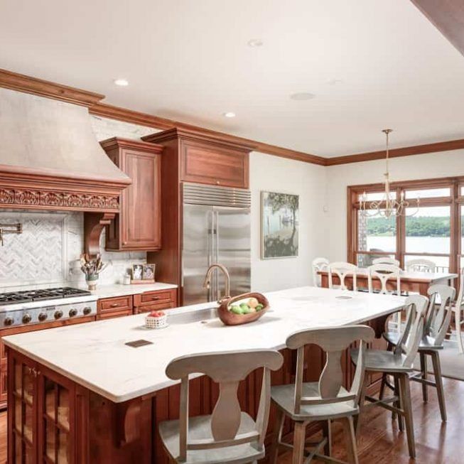 Bright kitchen with wooden cabinets, stainless fridge, large island, and dining table by a window