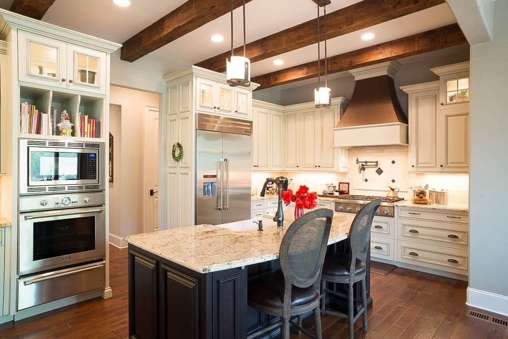 Bright modern kitchen with white cabinets, granite island, wood beams, and stainless steel appliances