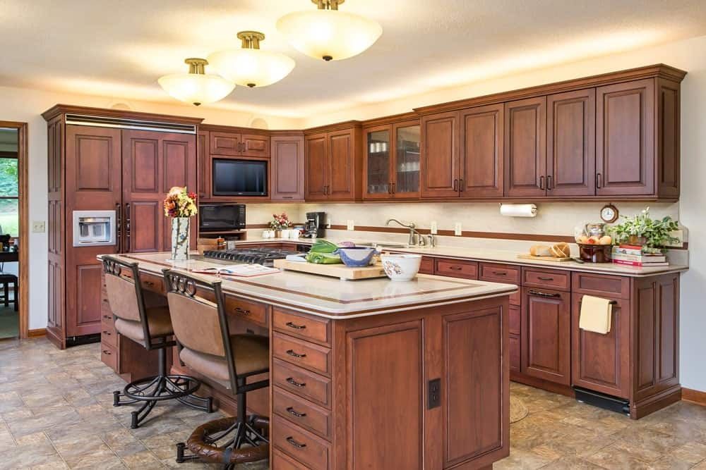 Spacious kitchen with wood cabinets, center island, bar stools, and warm ceiling lights.