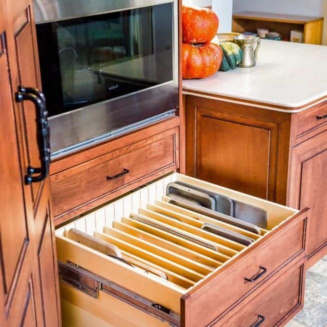 Kitchen cabinet drawer with file organizer pulled open beside a built-in microwave.