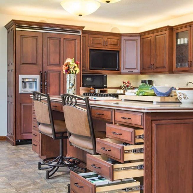 Modern kitchen with wooden cabinets, island drawers open, bar stools, and built-in appliances