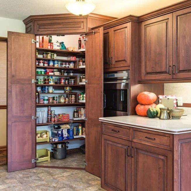 Open kitchen pantry with shelves of food and a countertop holding pumpkins and a bowl