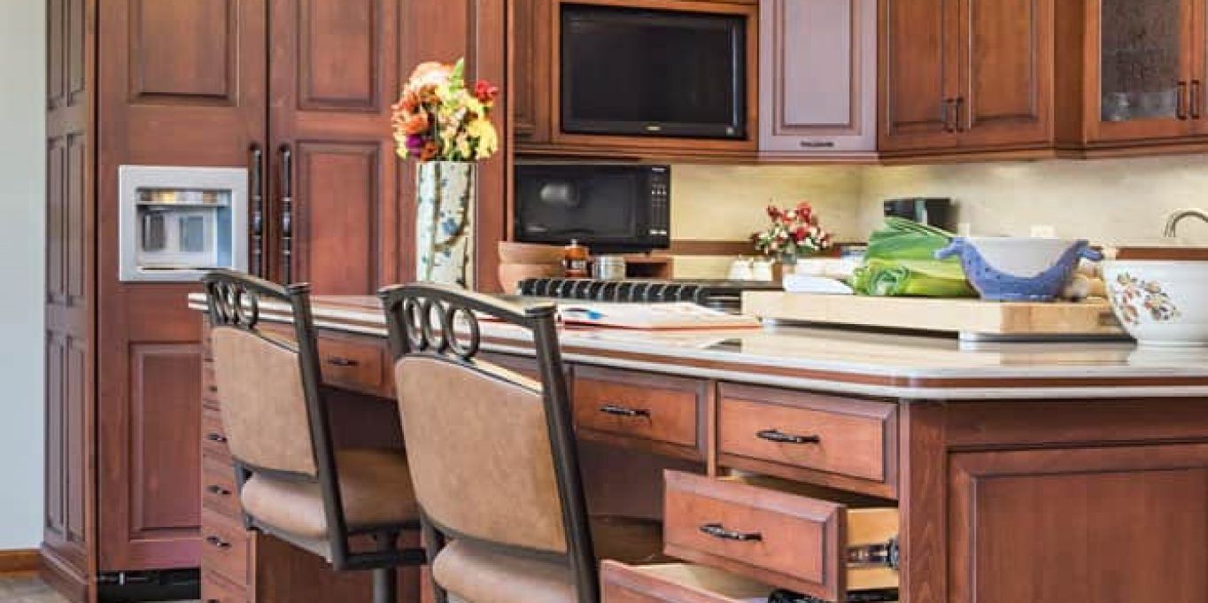 Kitchen island with two upholstered stools, wooden cabinets, and countertop decor