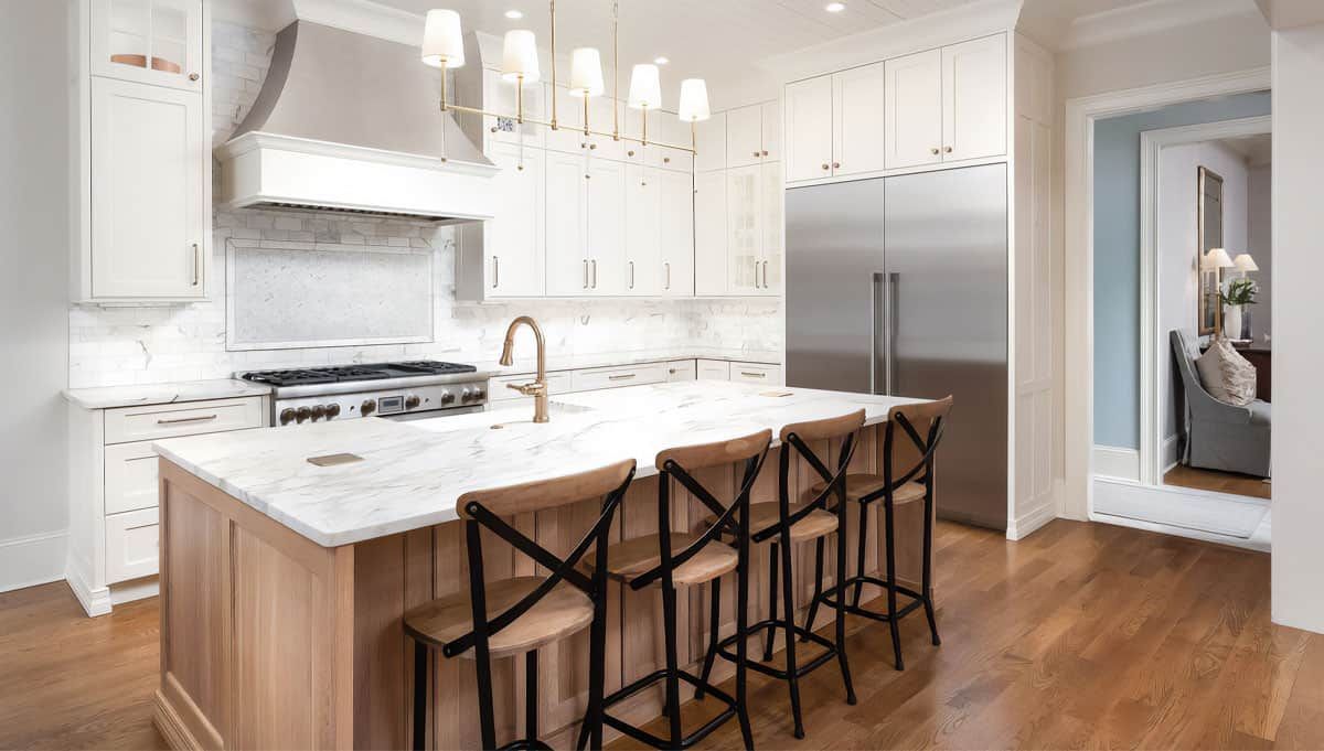 Bright white modern kitchen with island, pendant lights, wood stools, and hardwood floors
