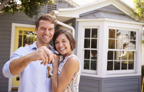 Couple with keys standing outside new home
