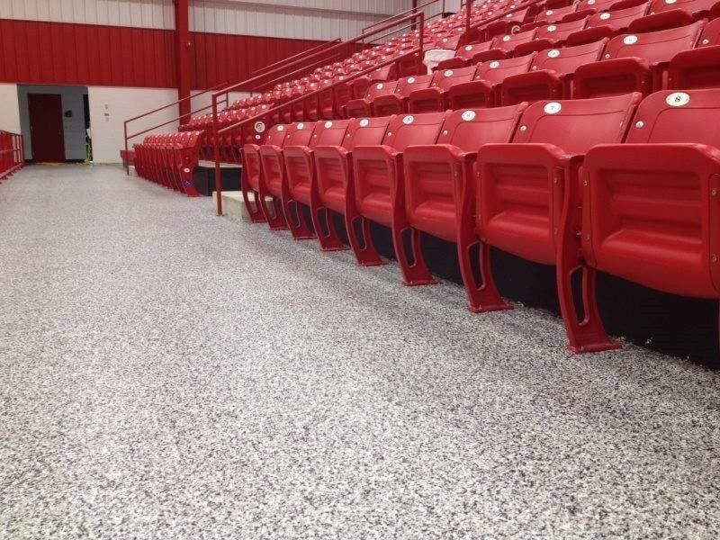 Rows of red seats in a stadium with a white floor