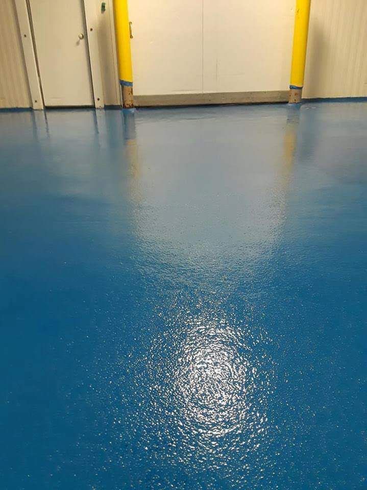 A blue floor in a room with a yellow pole in the background.