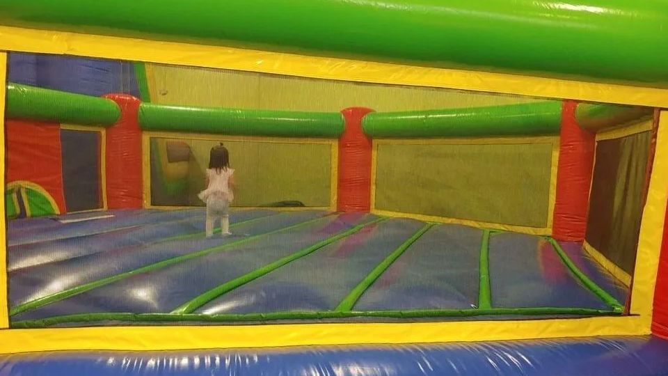 A little girl is playing in an inflatable bouncy house.