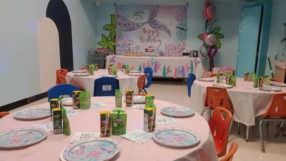 A room with tables and chairs set up for a birthday party.